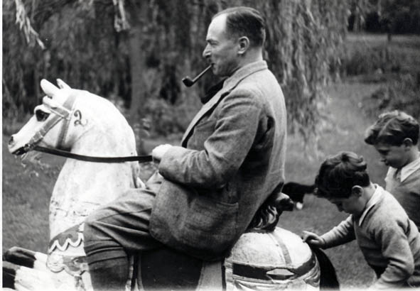 de Man zittend op een hobbelpaard met 2 kinderen. 1930 | Charnel-House